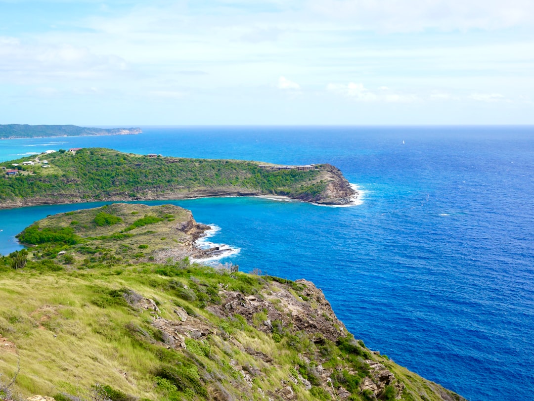 green-grass-field-near-blue-sea-under-blue-sky-during-daytime-odmu1fli6fw